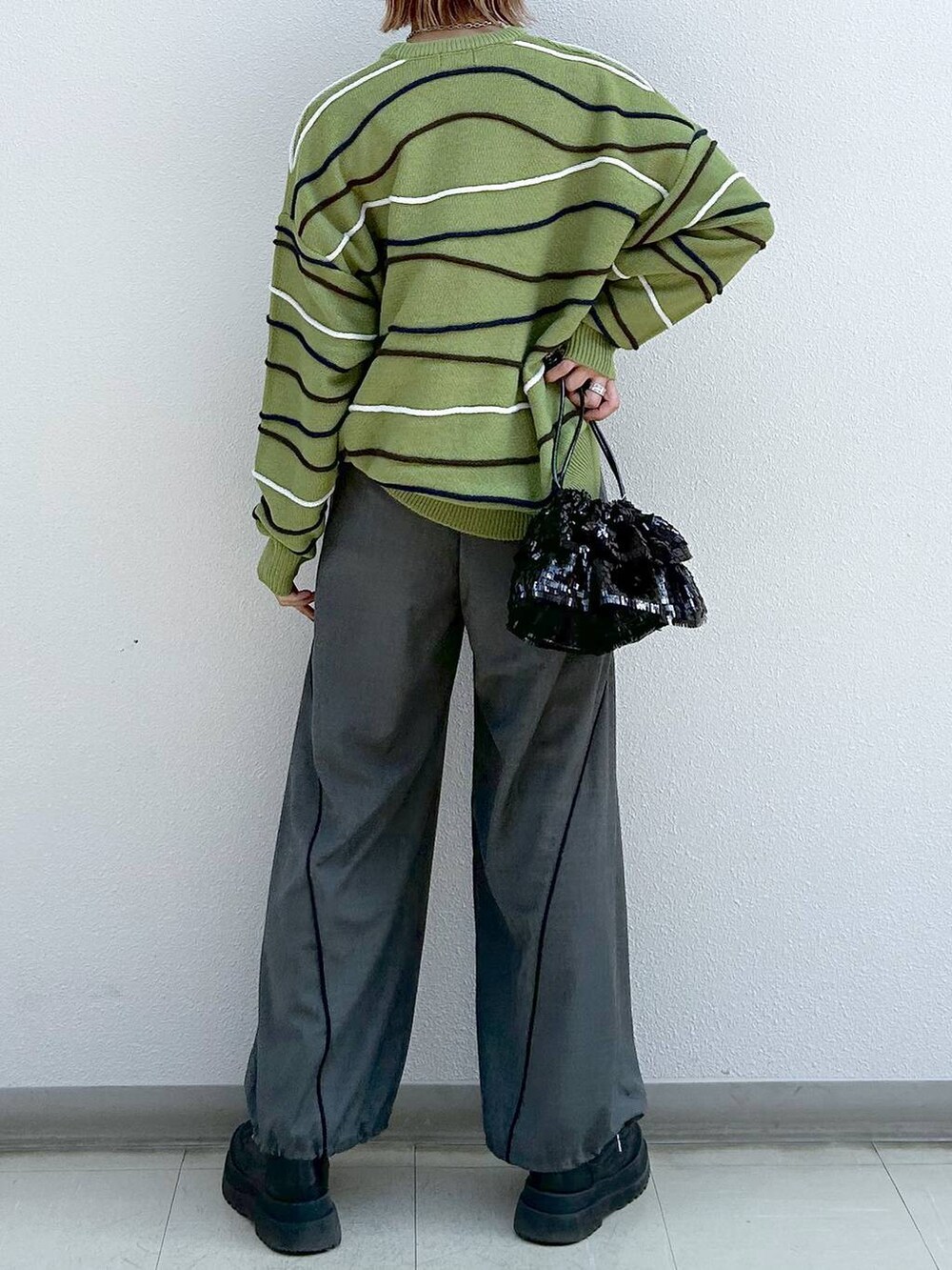 グレー系のその他パンツ、ブラック系のブーツ、グリーン系のニット/セーターを着用したレディースの冬コーディネートの6枚目の写真