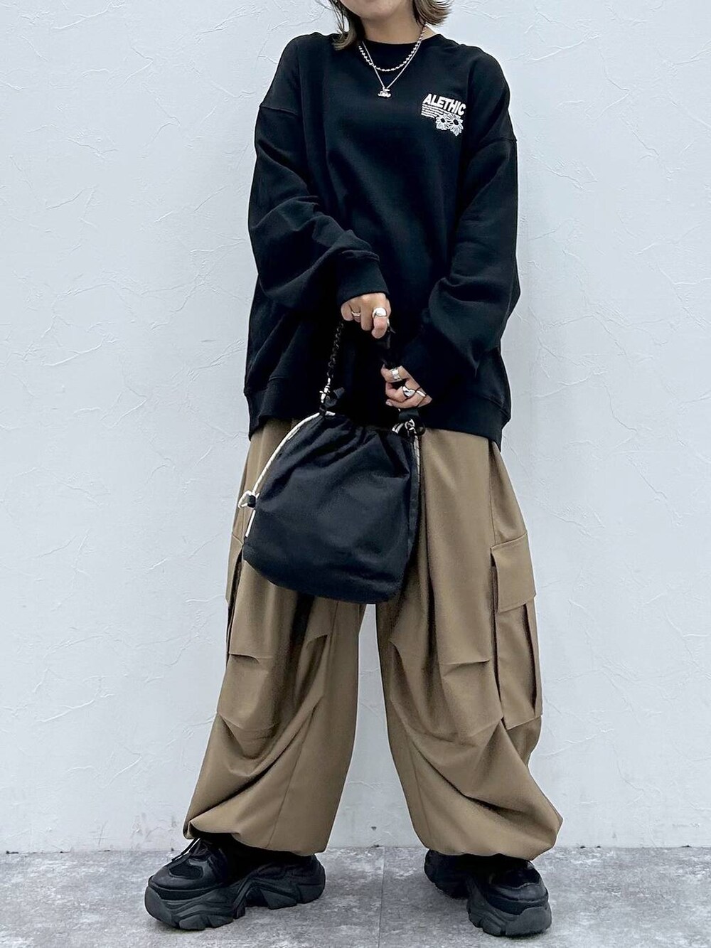 ブラック系のスニーカー、ブラック系のスウェット、ブラック系のショルダーバッグを着用したレディースの秋コーディネートの4枚目の写真