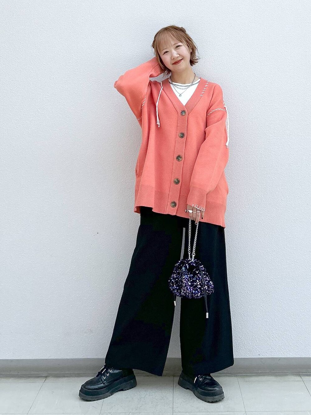 ブラック系のスラックス、ホワイト系のタンクトップ、ブラック系のブーツを着用したレディースの冬コーディネートの7枚目の写真