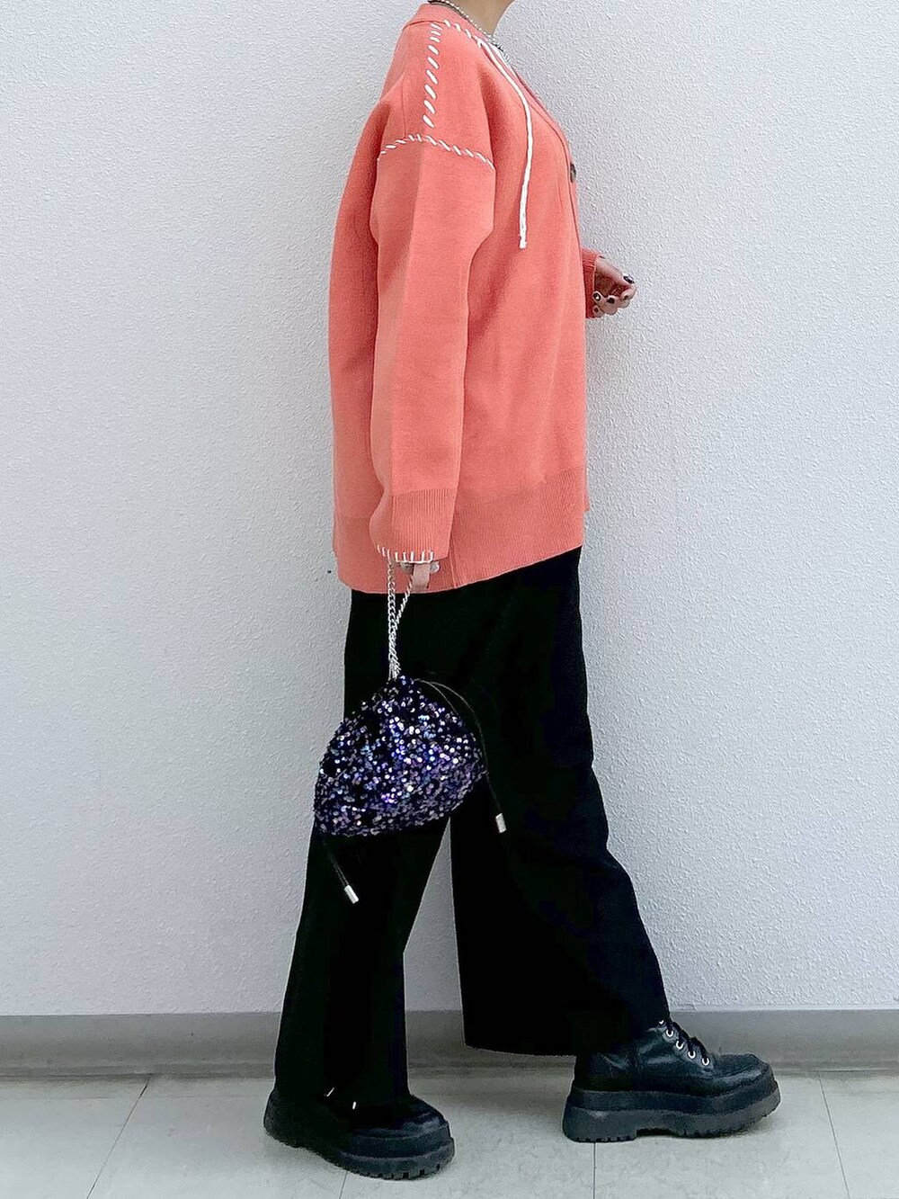 ブラック系のスラックス、ホワイト系のタンクトップ、ブラック系のブーツを着用したレディースの冬コーディネートの5枚目の写真