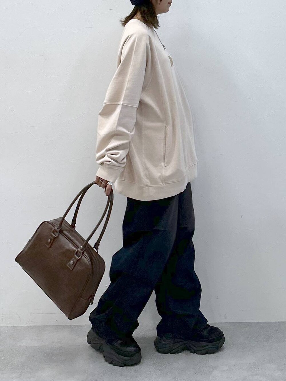 ブラック系のスニーカー、ブルー系のデニムパンツ、ブラウン系のボストンバッグを着用したレディースの冬コーディネートの5枚目の写真