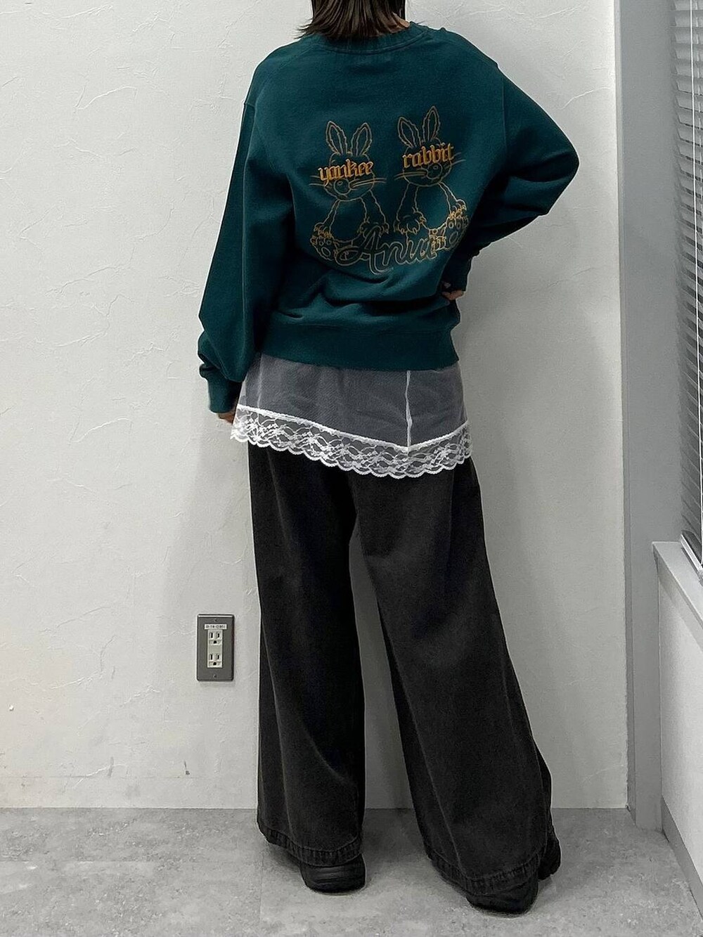 ブラック系のスニーカー、ブラック系のデニムパンツ、グリーン系のスウェットを着用したレディースの冬コーディネートの6枚目の写真