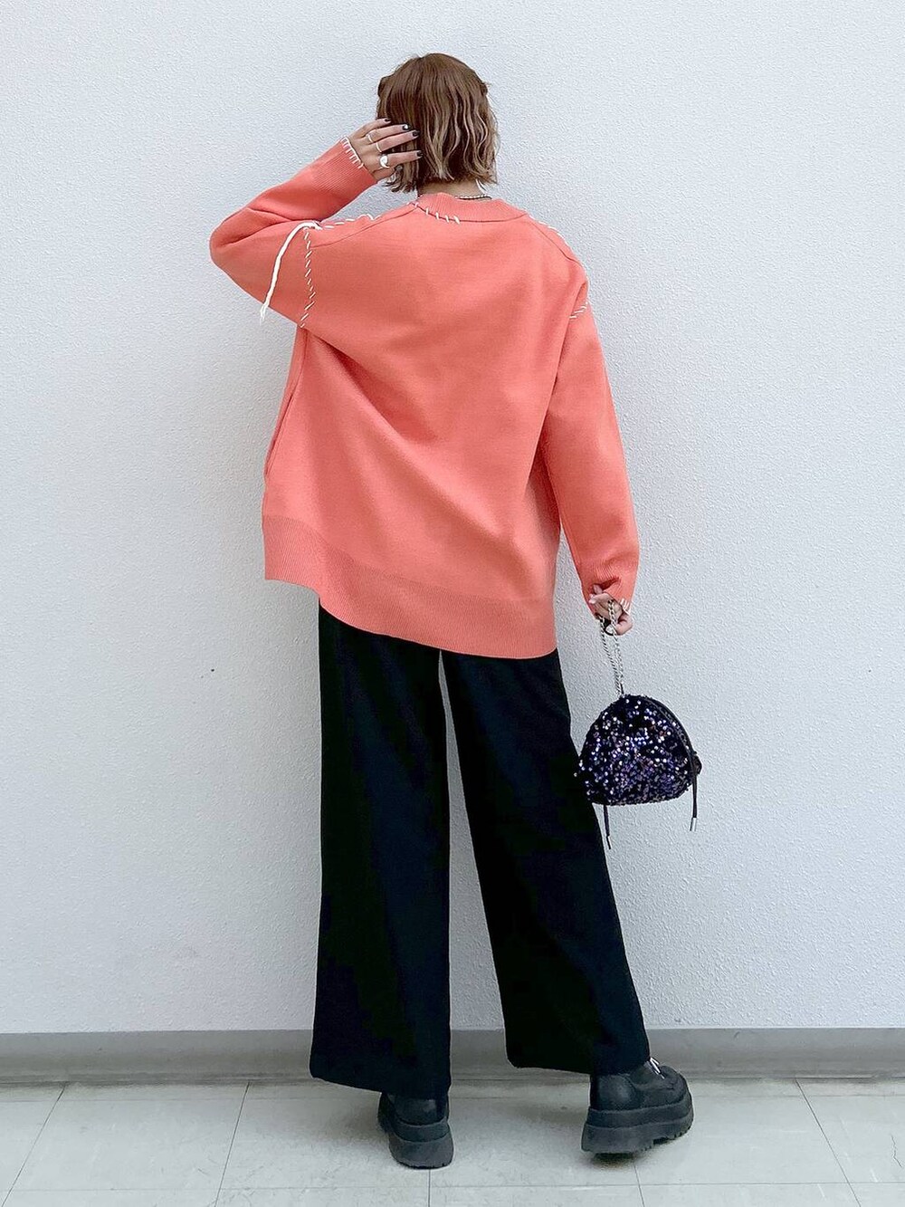 ブラック系のスラックス、ホワイト系のタンクトップ、ブラック系のブーツを着用したレディースの冬コーディネートの3枚目の写真