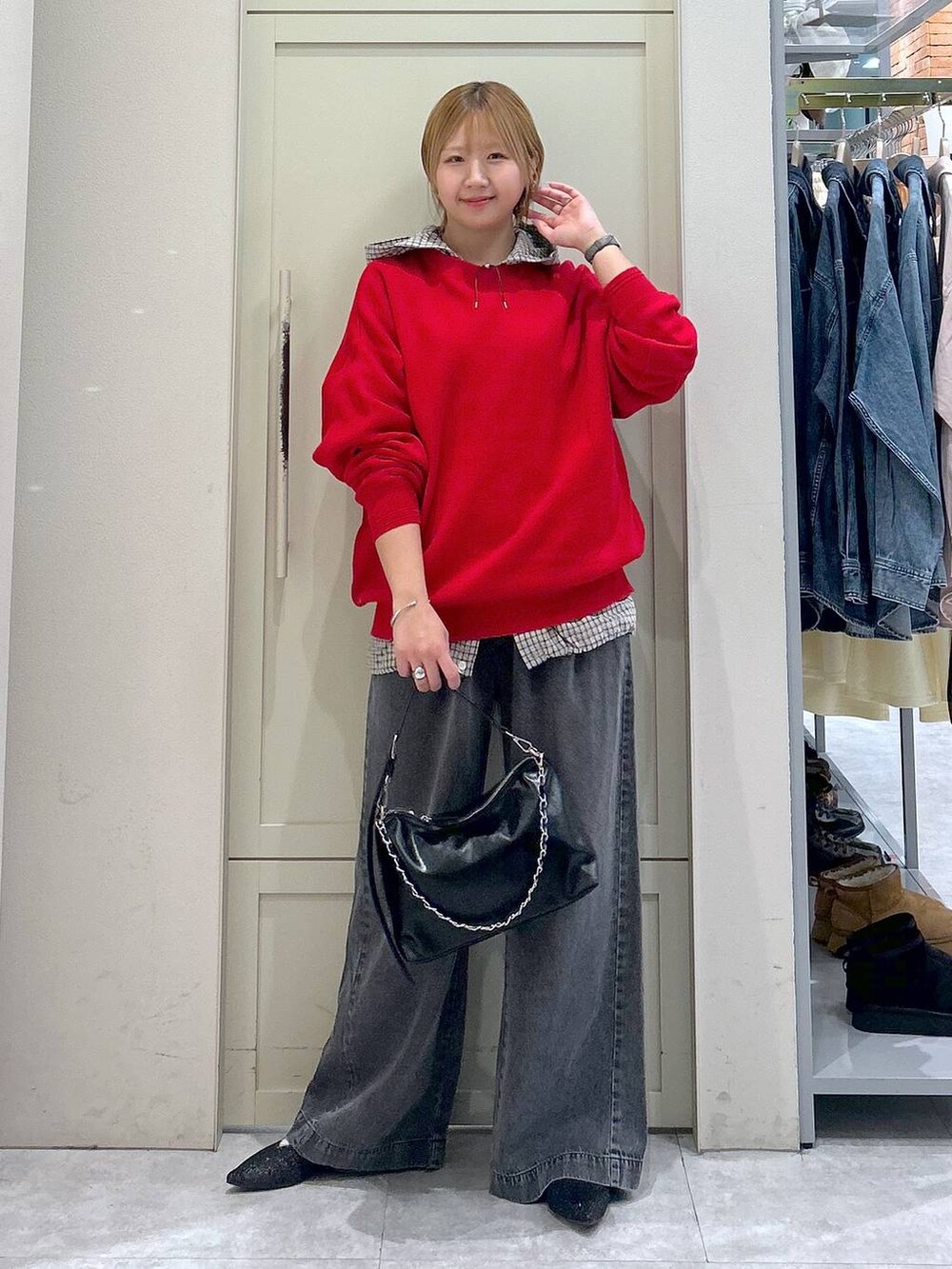 ブラック系のデニムパンツ、レッド系のニット/セーター、ブラック系のショルダーバッグを着用したレディースの春コーディネートの7枚目の写真