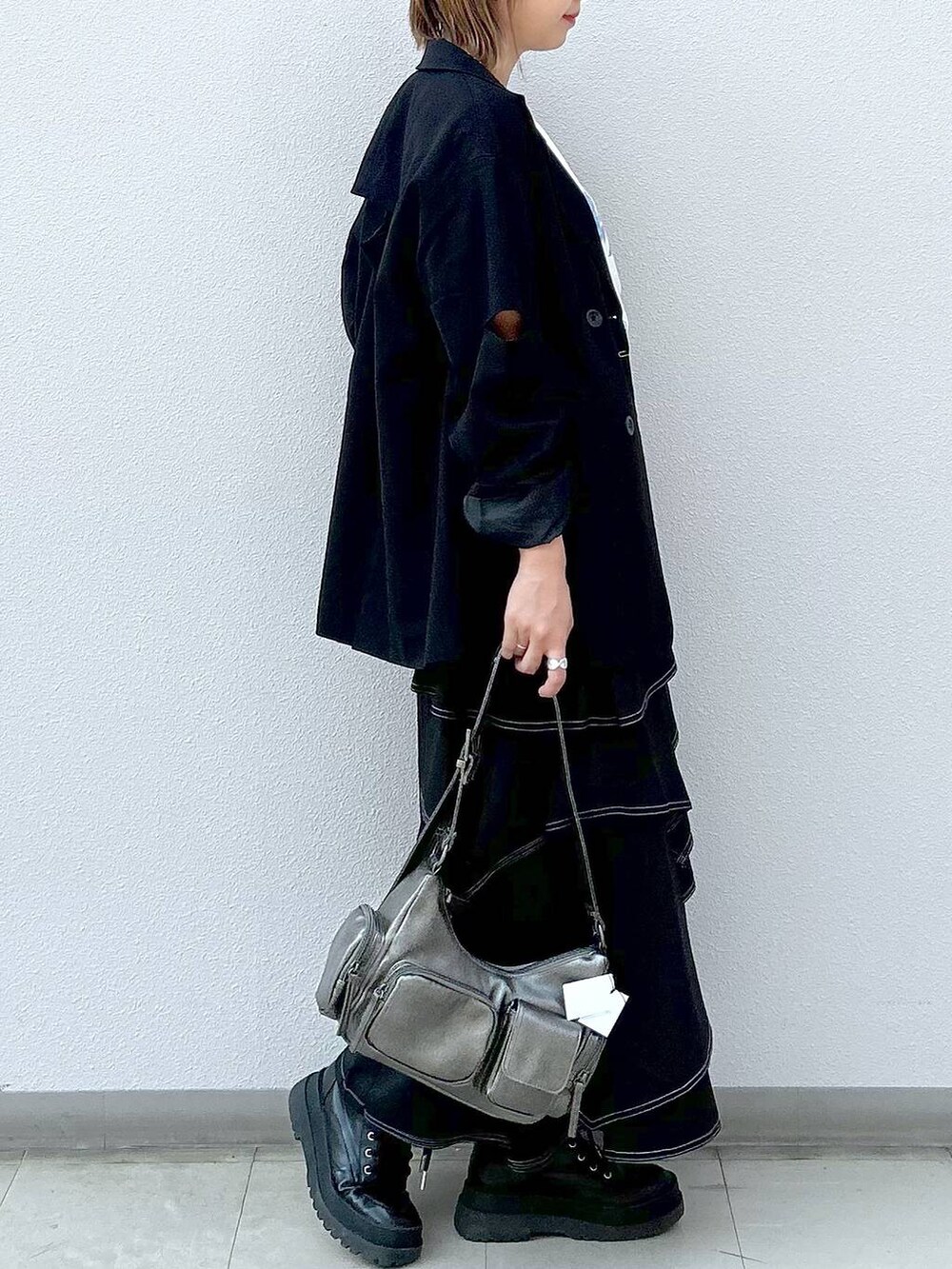 ブラック系のテーラードジャケット、ブラック系のブーツ、ベージュ系のTシャツ/カットソーを着用したレディースの秋コーディネートの5枚目の写真