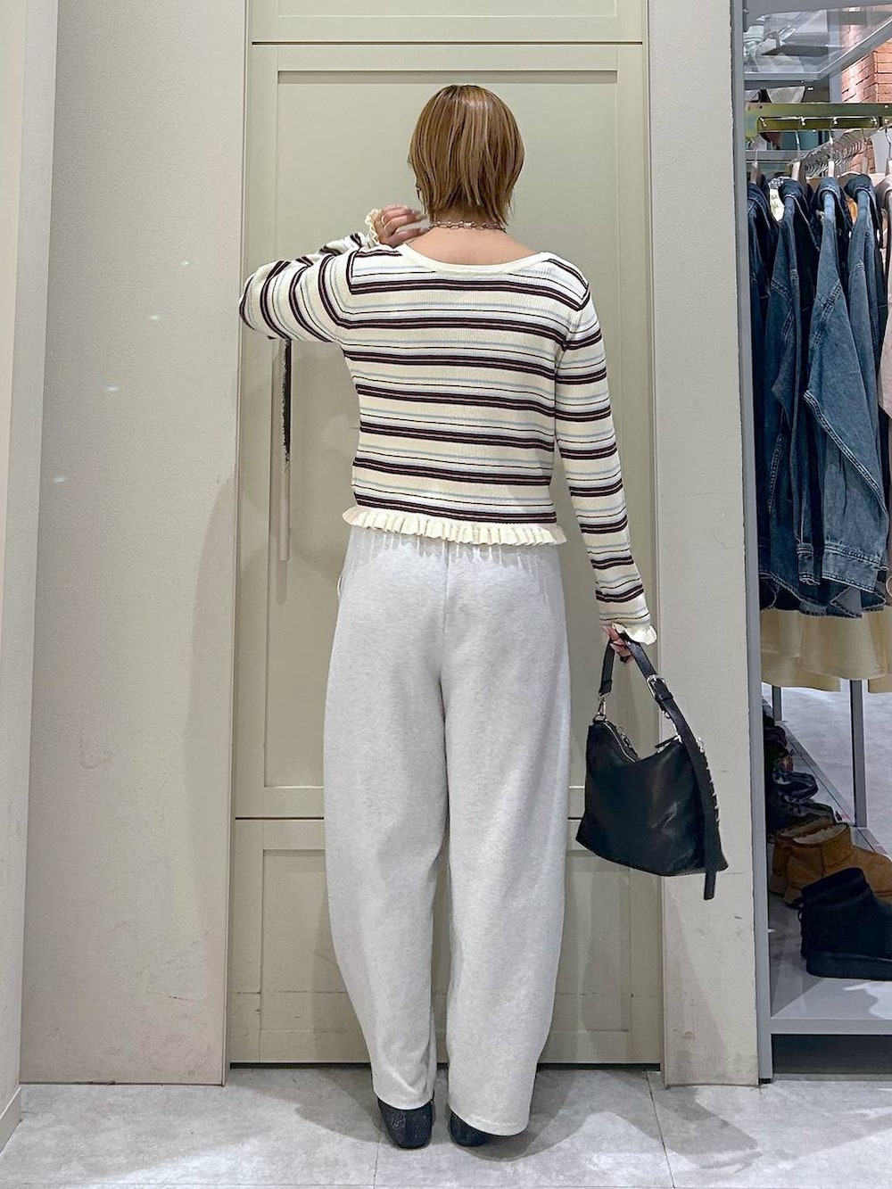 グレー系のスウェットパンツ、ブラック系のショルダーバッグ、ブラック系のパンプスを着用したレディースの冬コーディネートの3枚目の写真