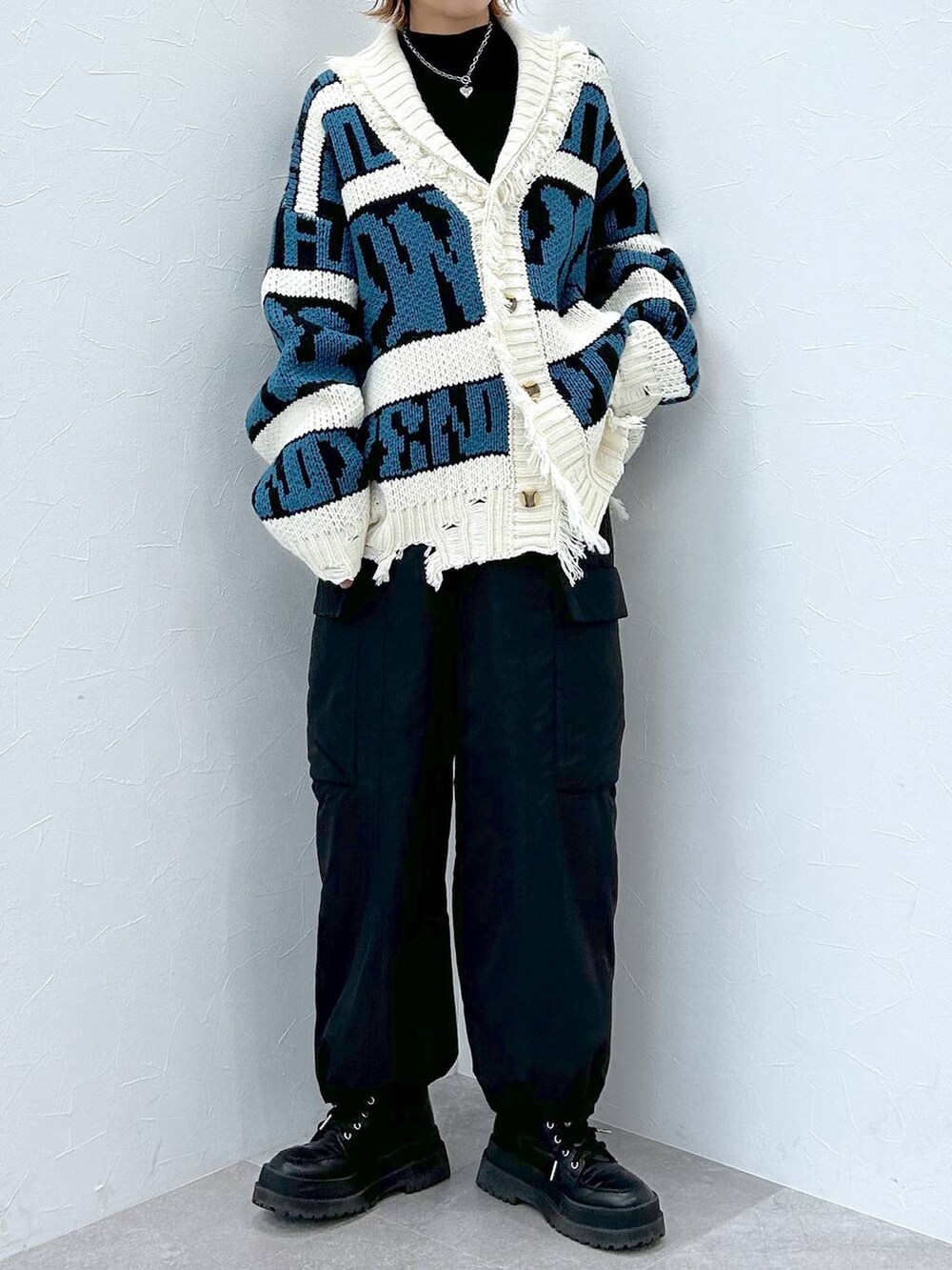 ブラック系のブーツ、ブラック系のニット/セーター、ブラック系のカーゴパンツを着用したレディースの冬コーディネートの4枚目の写真