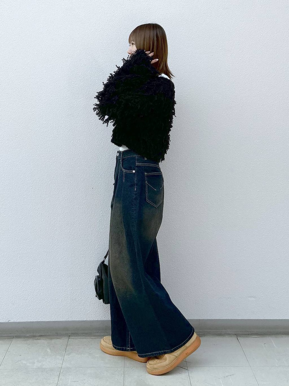 ブラック系のショルダーバッグ、ブラック系のカーディガン/ボレロ、ホワイト系のTシャツ/カットソーを着用したレディースの冬コーディネートの2枚目の写真