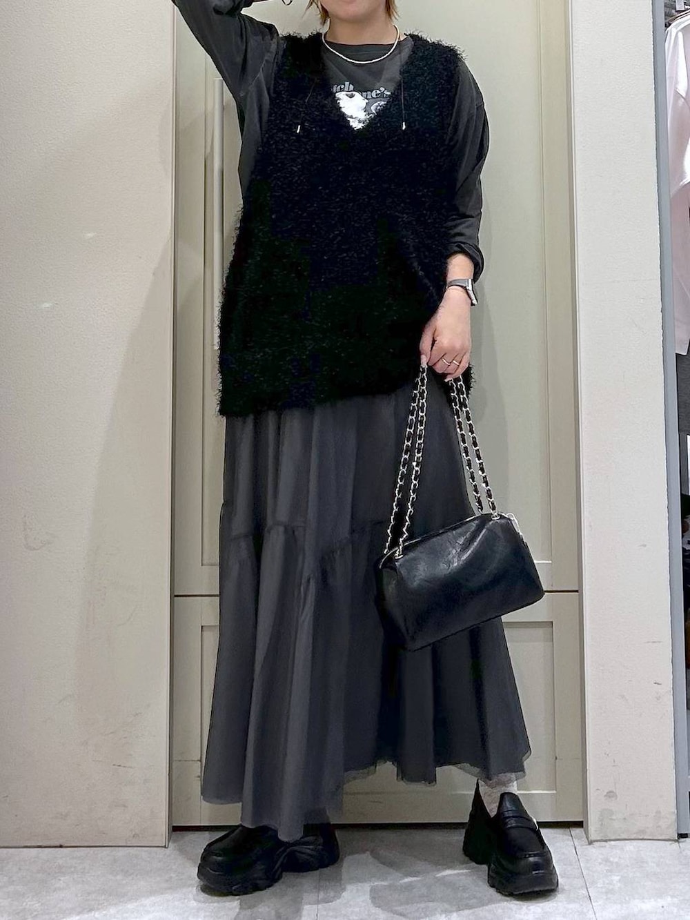 ブラック系のショルダーバッグ、ブラック系のローファー、ブラック系のベストを着用したレディースの春コーディネートの4枚目の写真