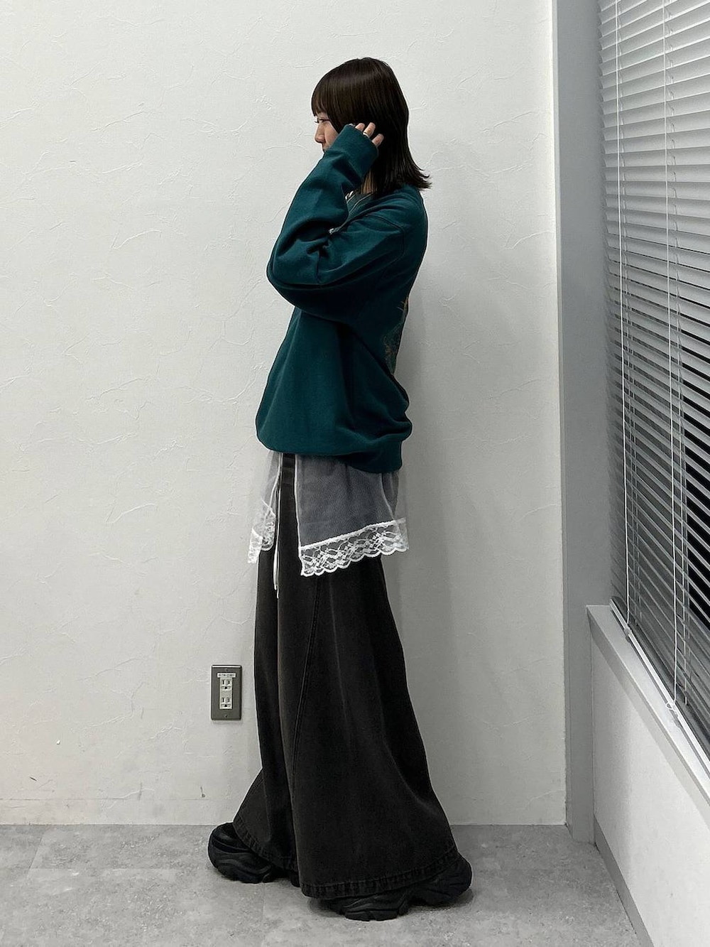 ブラック系のスニーカー、ブラック系のデニムパンツ、グリーン系のスウェットを着用したレディースの冬コーディネートの2枚目の写真