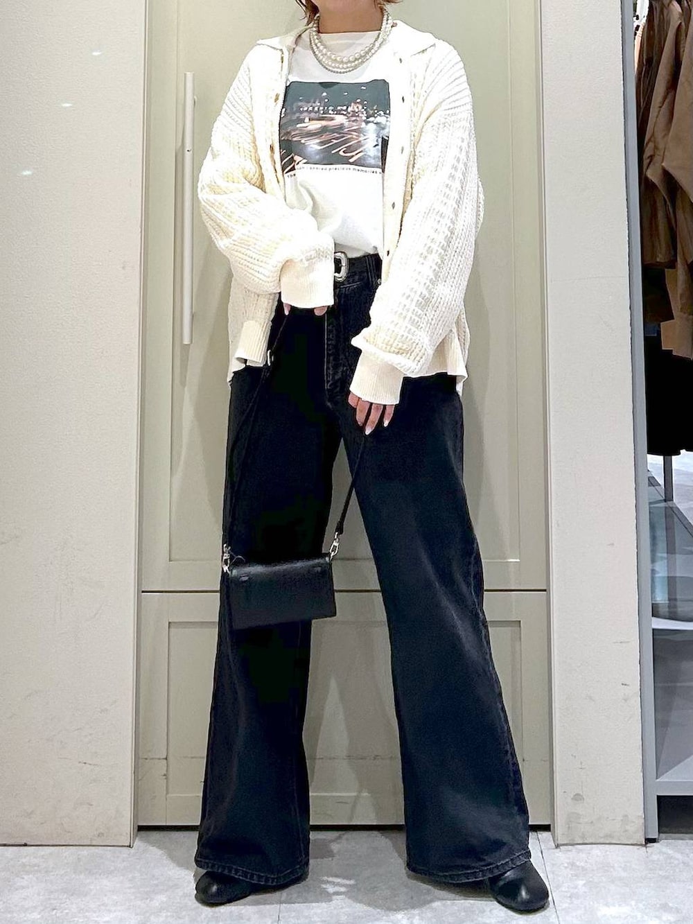 ブラック系のデニムパンツ、ブラック系のサンダル、ブラック系のボディバッグ/ウエストポーチを着用したレディースの春コーディネートの4枚目の写真