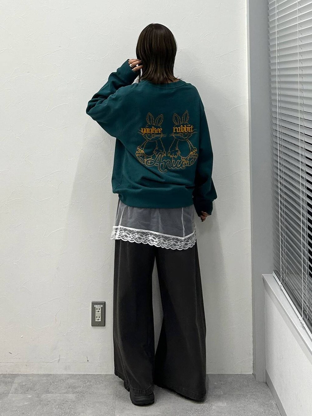 ブラック系のスニーカー、ブラック系のデニムパンツ、グリーン系のスウェットを着用したレディースの冬コーディネートの3枚目の写真