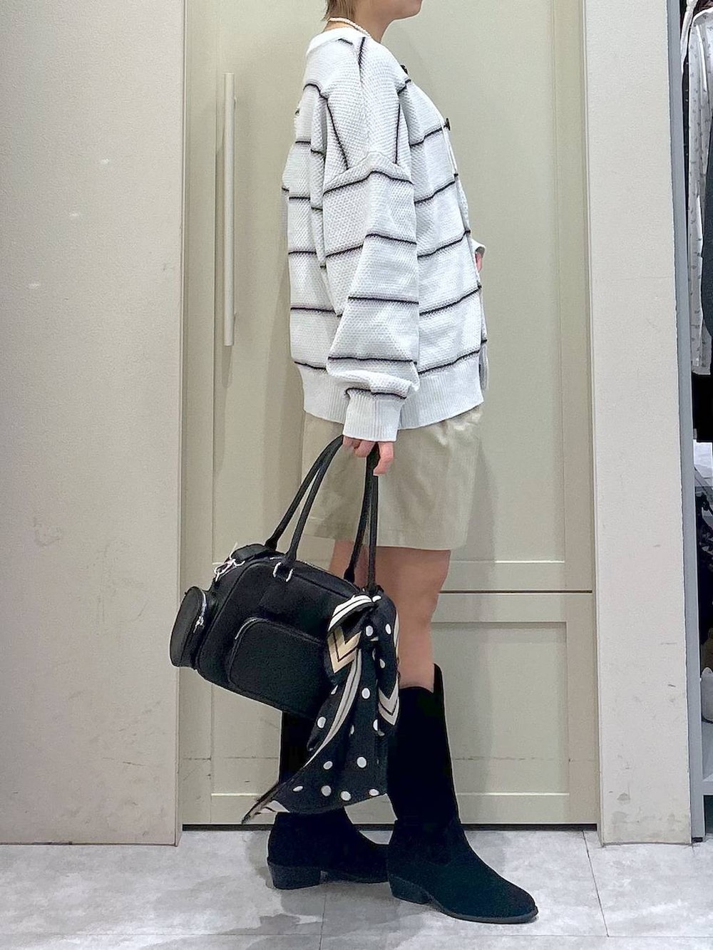 ホワイト系のキャミソール、ブラック系のブーツ、ブラック系のボストンバッグを着用したレディースの春コーディネートの4枚目の写真