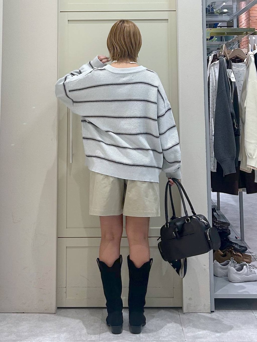 ホワイト系のキャミソール、ブラック系のブーツ、ブラック系のボストンバッグを着用したレディースの春コーディネートの3枚目の写真