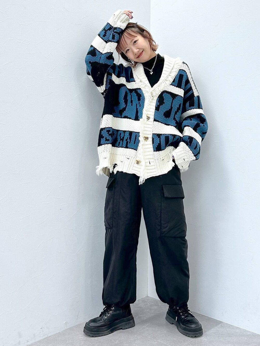 ブラック系のブーツ、ブラック系のニット/セーター、ブラック系のカーゴパンツを着用したレディースの冬コーディネートの7枚目の写真