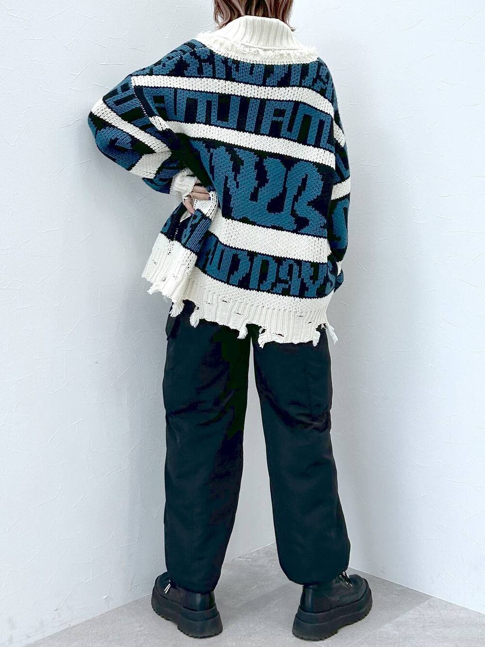 ブラック系のブーツ、ブラック系のニット/セーター、ブラック系のカーゴパンツを着用したレディースの冬コーディネートの6枚目の写真