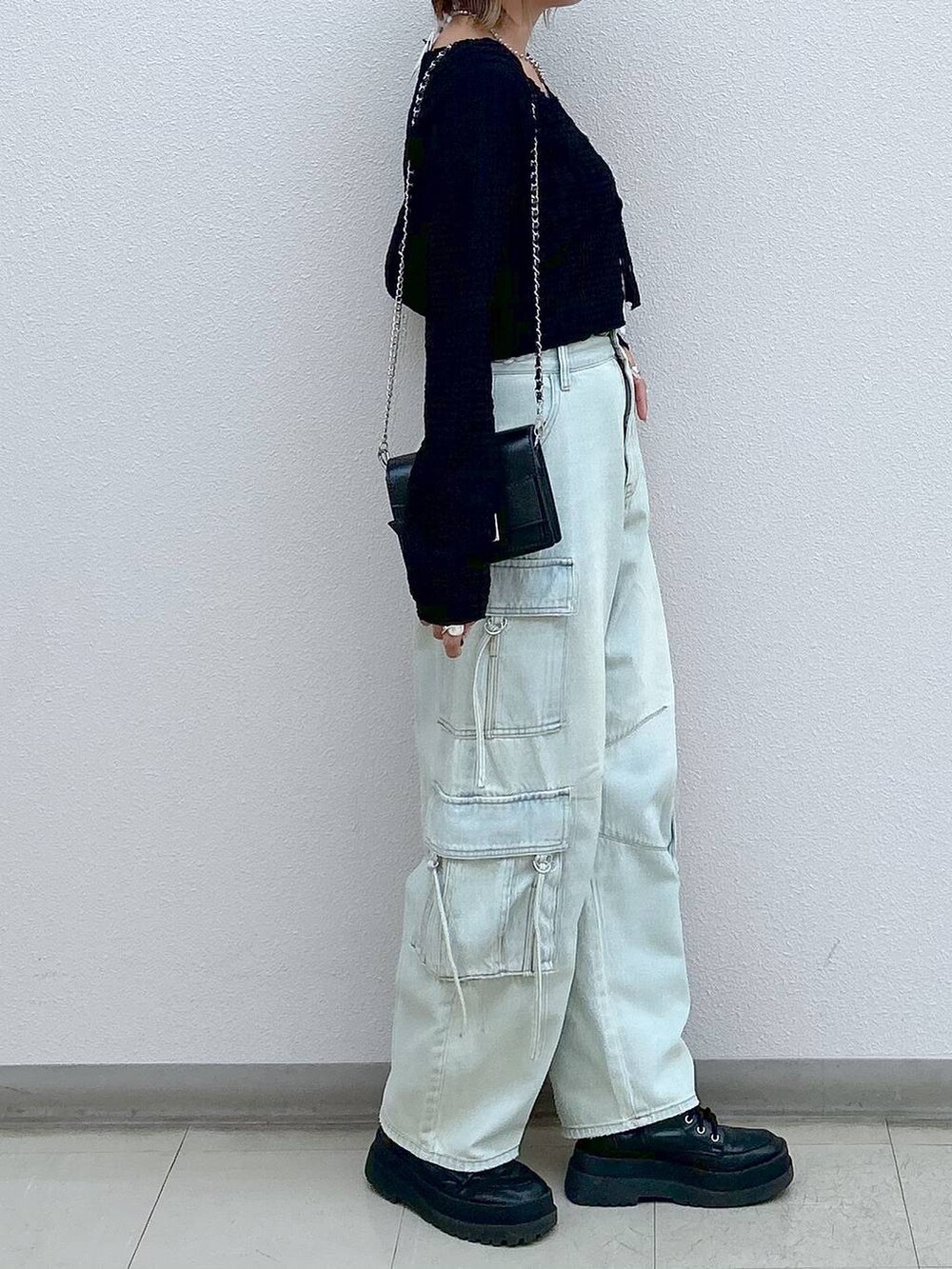 ブラック系のブーツ、ブルー系のデニムパンツ、ブラック系のショルダーバッグを着用したレディースの秋コーディネートの4枚目の写真