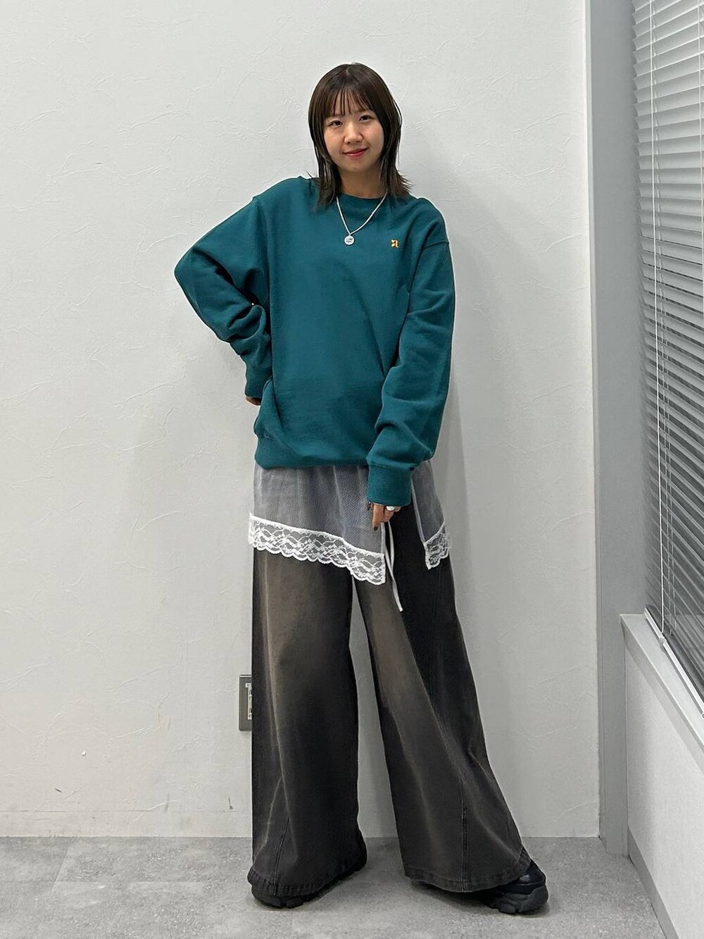 ブラック系のスニーカー、ブラック系のデニムパンツ、グリーン系のスウェットを着用したレディースの冬コーディネートの7枚目の写真