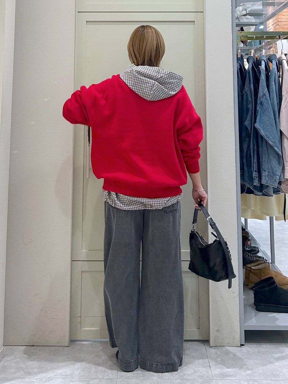 ブラック系のデニムパンツ、レッド系のニット/セーター、ブラック系のショルダーバッグを着用したレディースの春コーディネートの3枚目の写真