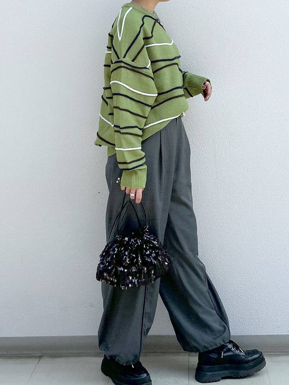 グレー系のその他パンツ、ブラック系のブーツ、グリーン系のニット/セーターを着用したレディースの冬コーディネートの5枚目の写真