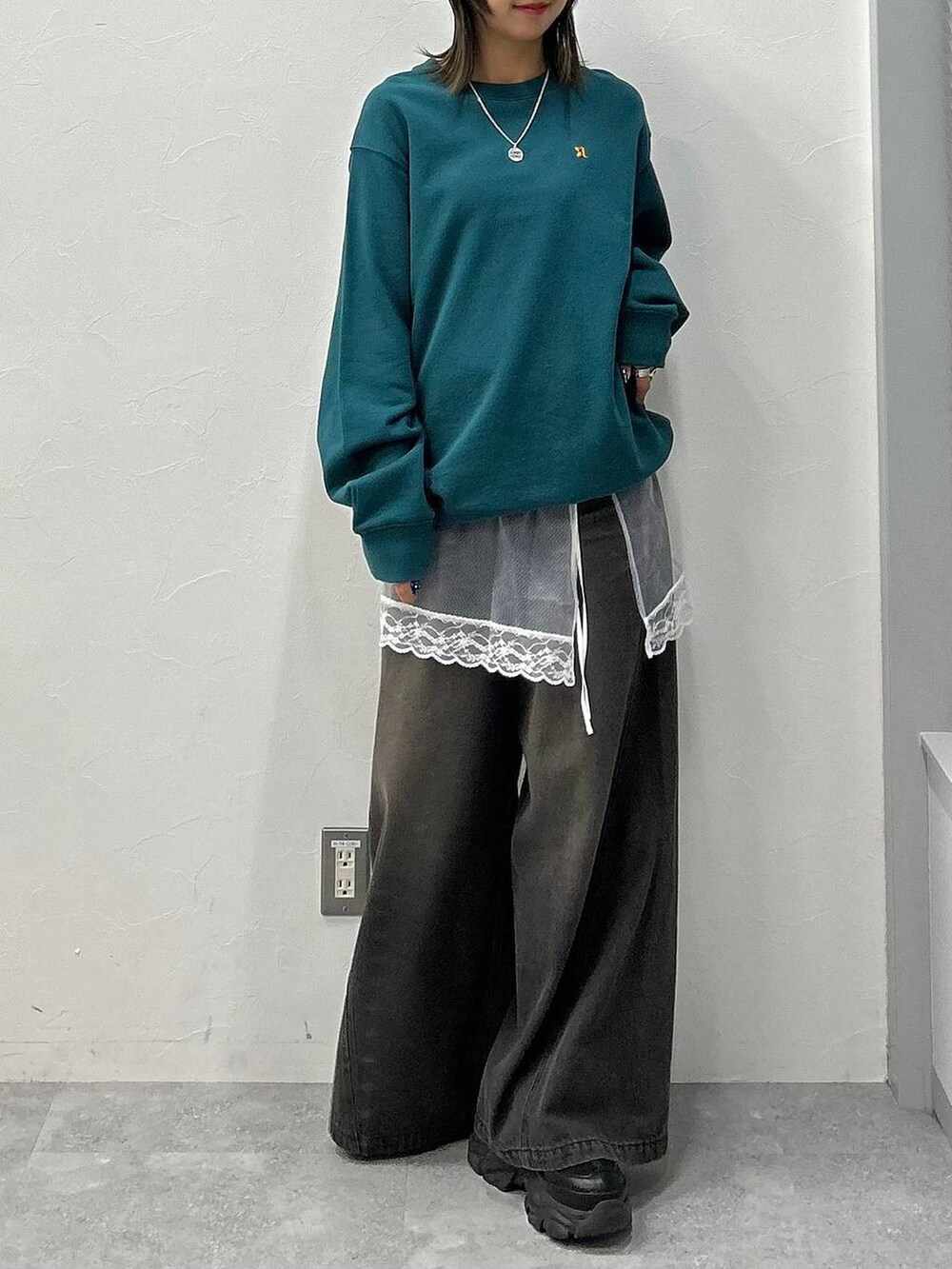 ブラック系のスニーカー、ブラック系のデニムパンツ、グリーン系のスウェットを着用したレディースの冬コーディネートの4枚目の写真