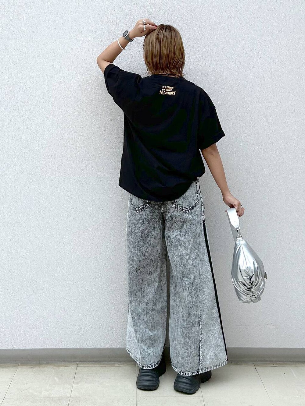 ブラック系のスニーカー、グレー系のデニムパンツ、シルバー系のショルダーバッグを着用したレディースの夏コーディネートの3枚目の写真