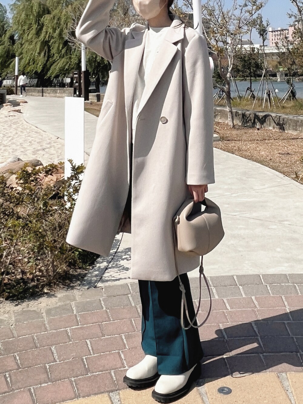 グレー系のスウェット、グレー系のチェスターコート、グリーン系のパンツを着用したレディースの冬コーディネートの2枚目の写真