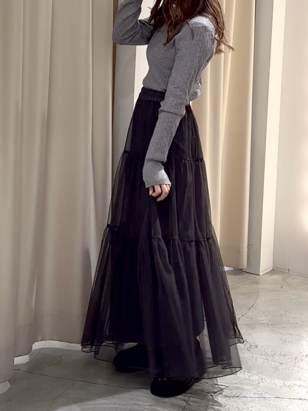 グレー系のニット/セーター、ブラック系のステンカラーコートを着用したレディースの冬コーディネートの10枚目の写真