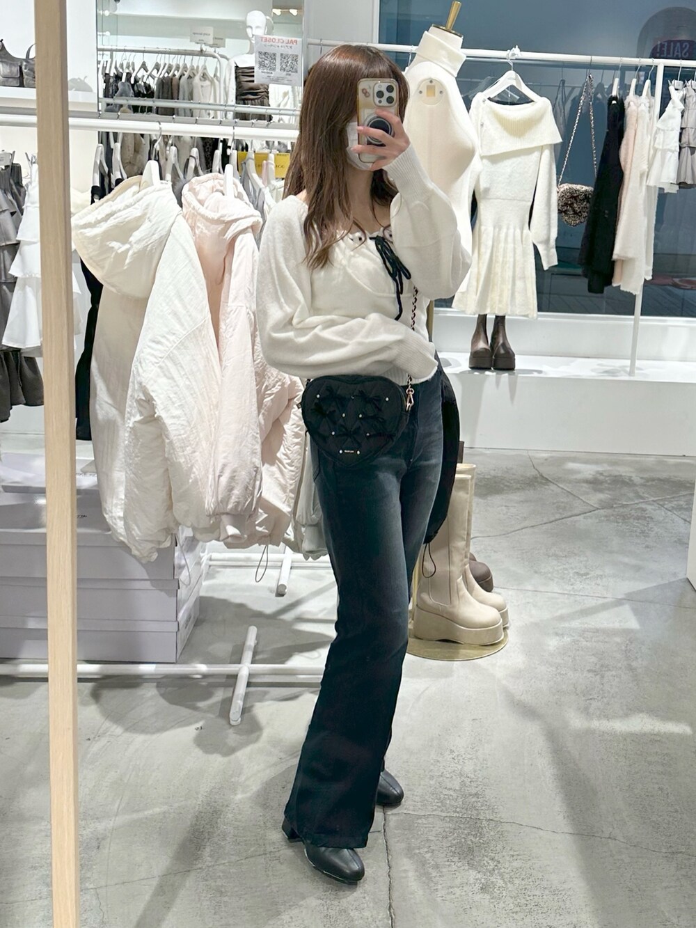 ブルー系のデニムパンツ、ホワイト系のニット/セーター、ブラック系のショルダーバッグを着用したレディースの冬コーディネートの2枚目の写真