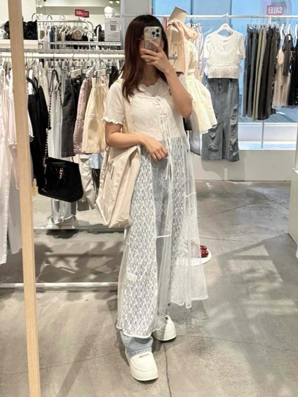 ホワイト系のワンピース、ブルー系のデニムパンツ、ホワイト系のトートバッグを着用したレディースの夏コーディネートの10枚目の写真