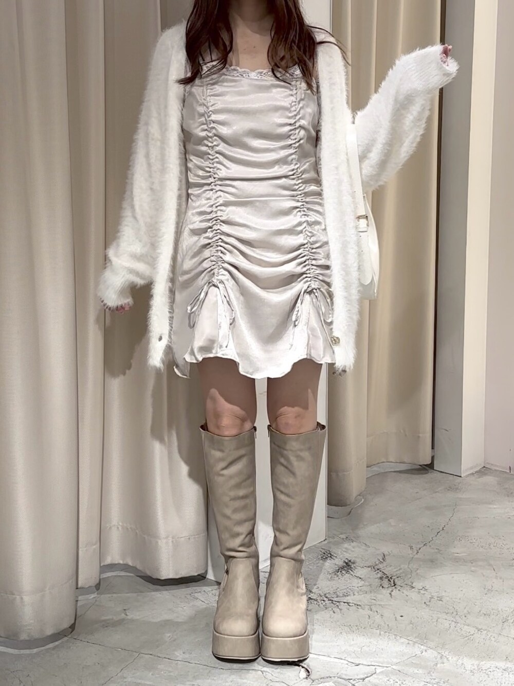 ホワイト系のカーディガン/ボレロ、ベージュ系のブーツ、ホワイト系のショルダーバッグを着用したレディースの秋コーディネートの2枚目の写真