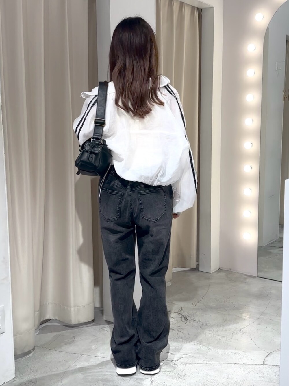 ホワイト系のブルゾン、ホワイト系のキャミソール、グレー系のデニムパンツを着用したレディースの夏コーディネートの9枚目の写真