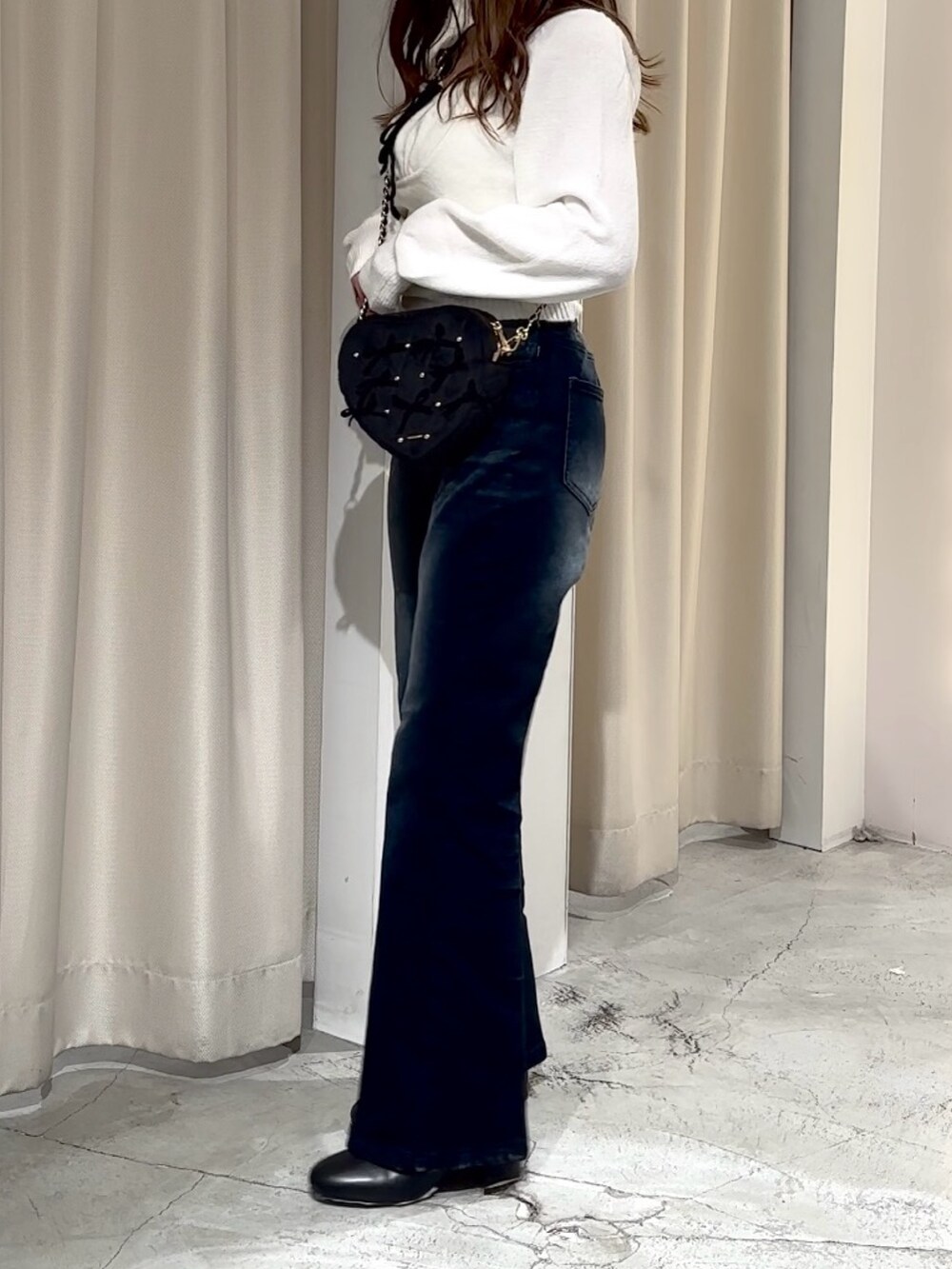 ブルー系のデニムパンツ、ホワイト系のニット/セーター、ブラック系のショルダーバッグを着用したレディースの冬コーディネートの6枚目の写真