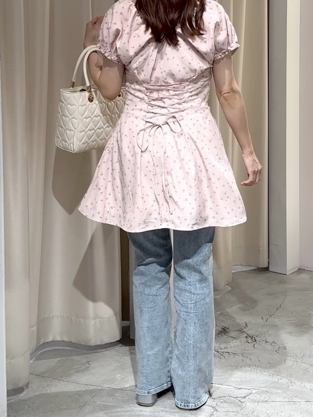 ピンク系のワンピース、ブルー系のデニムパンツ、シルバー系のパンプスを着用したレディースの夏コーディネートの5枚目の写真