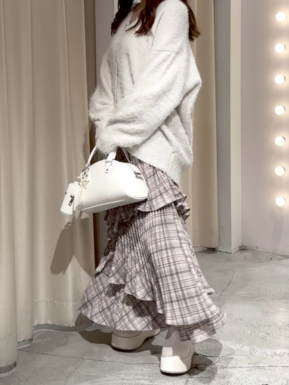 ホワイト系のハンドバッグ、ホワイト系のカーディガン/ボレロ、ブラウン系のスカートを着用したレディースの冬コーディネートの4枚目の写真