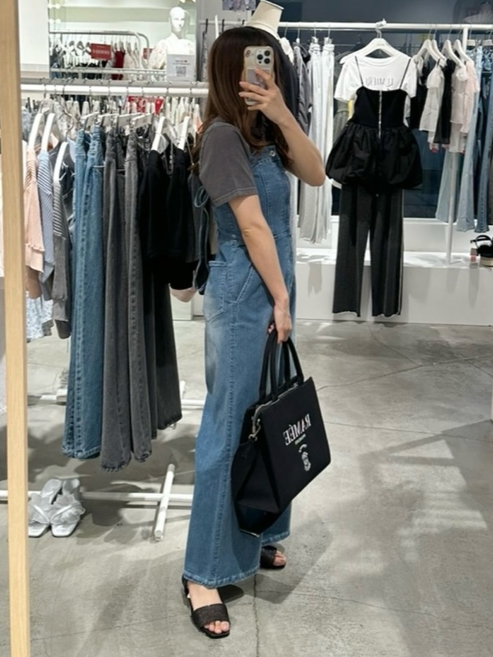 ブルー系のサロペット/オーバーオール、ブラック系のTシャツ/カットソー、ブラック系のサンダルを着用したレディースの夏コーディネートの5枚目の写真