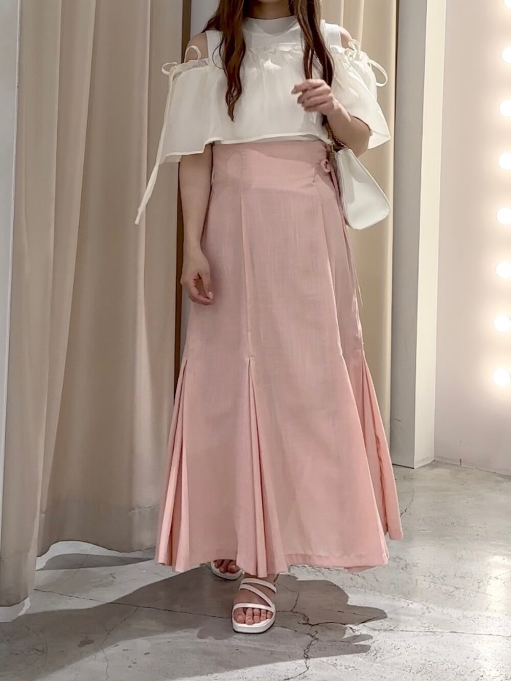 ホワイト系のニット/セーター、ピンク系のスカート、ホワイト系のサンダルを着用したレディースの夏コーディネートの4枚目の写真