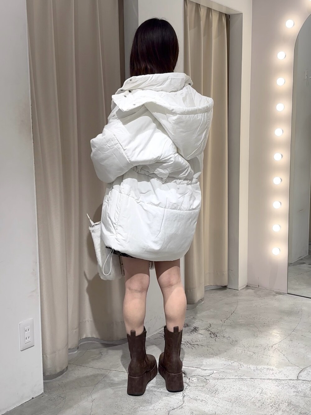 ホワイト系のダウンジャケット/コート、ブラウン系のスカート、ベージュ系のニット/セーターを着用したレディースの冬コーディネートの3枚目の写真