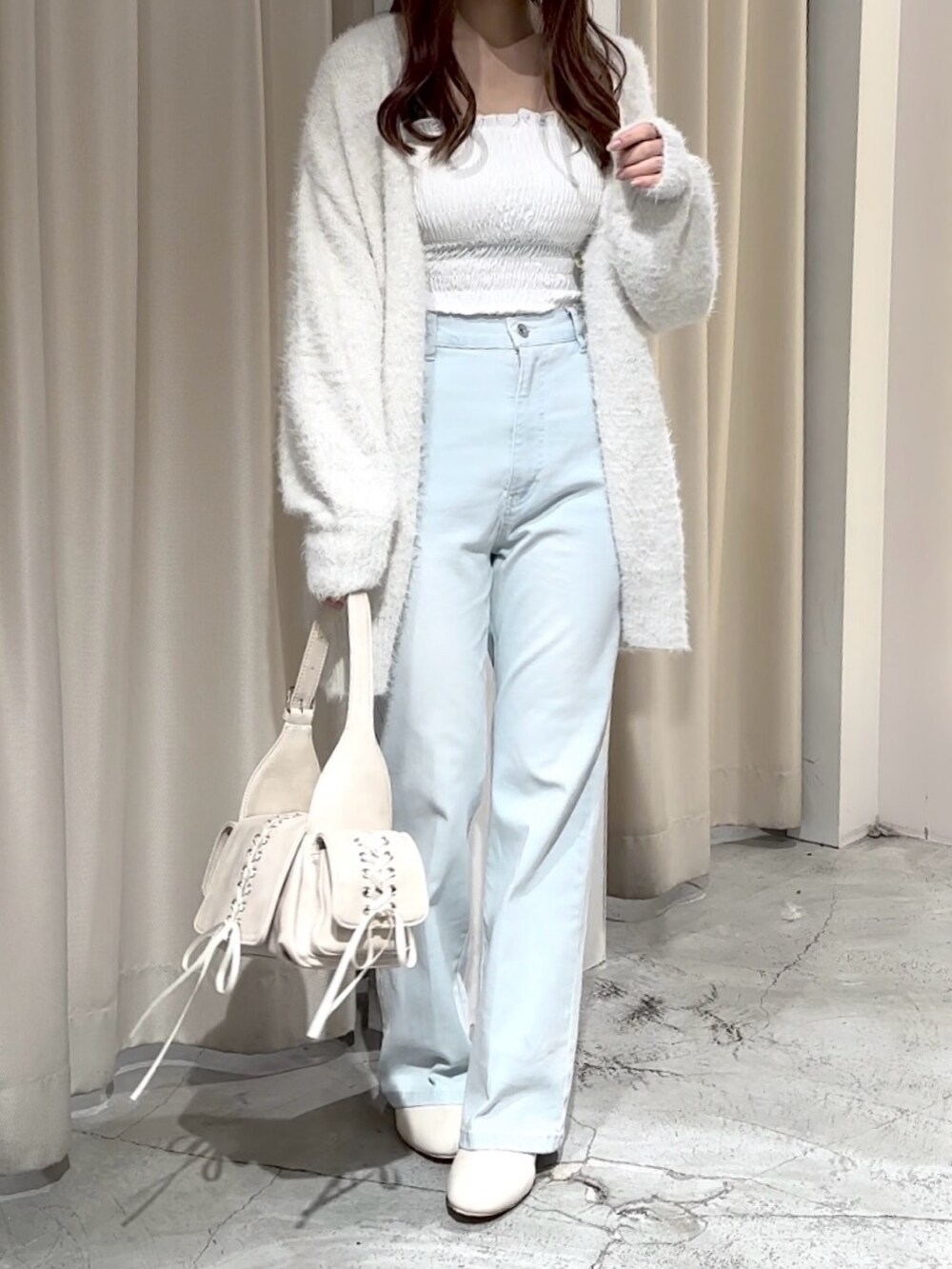 ホワイト系のショルダーバッグ、ホワイト系のカーディガン/ボレロ、ブルー系のデニムパンツを着用したレディースの冬コーディネートの4枚目の写真