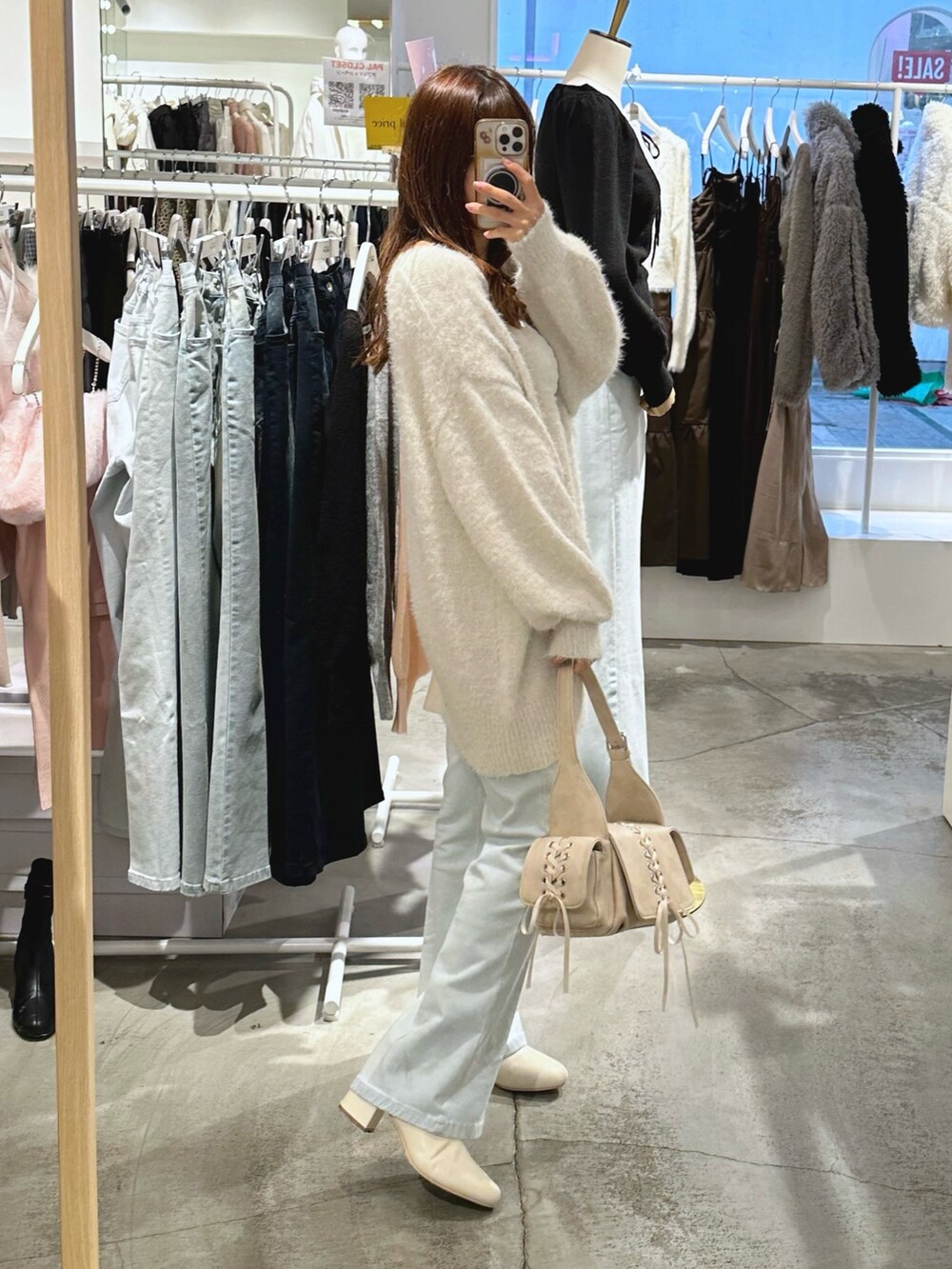 ホワイト系のショルダーバッグ、ホワイト系のカーディガン/ボレロ、ブルー系のデニムパンツを着用したレディースの冬コーディネートの3枚目の写真