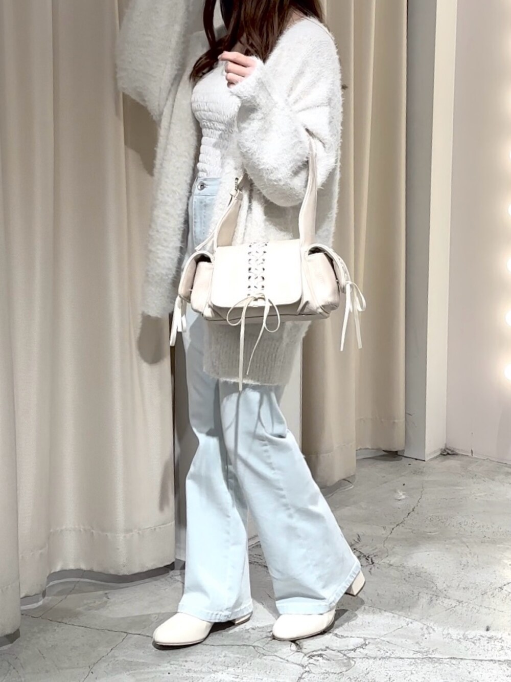 ホワイト系のショルダーバッグ、ホワイト系のカーディガン/ボレロ、ブルー系のデニムパンツを着用したレディースの冬コーディネートの5枚目の写真