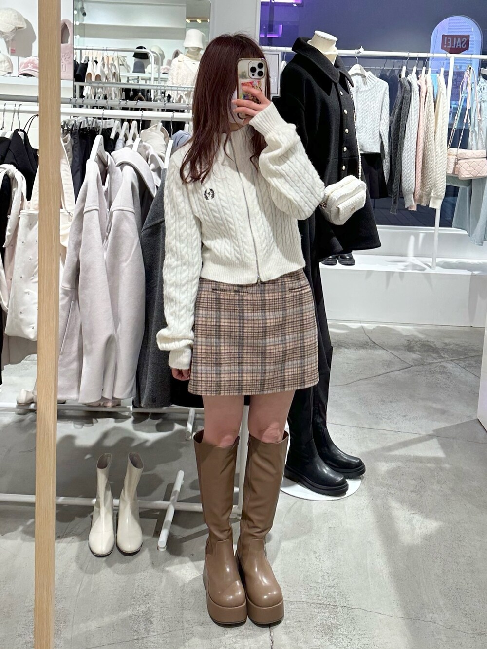 ホワイト系のニット/セーター、ベージュ系のスカート、ブラウン系のブーツを着用したレディースの冬コーディネートの2枚目の写真