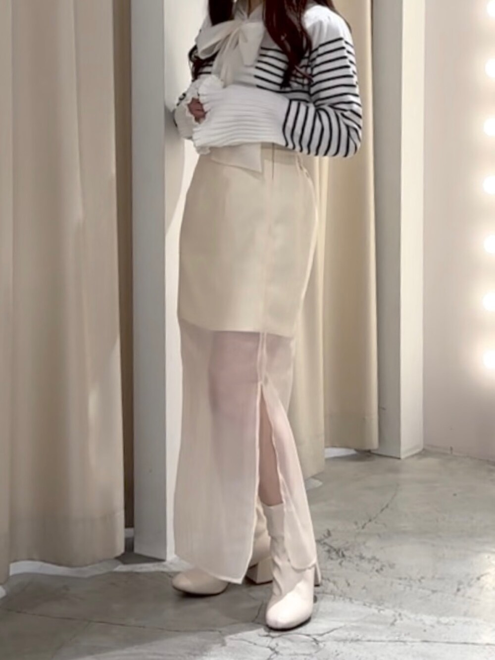 ブラック系のニット/セーター、ホワイト系のスカートを着用したレディースの冬コーディネートの2枚目の写真