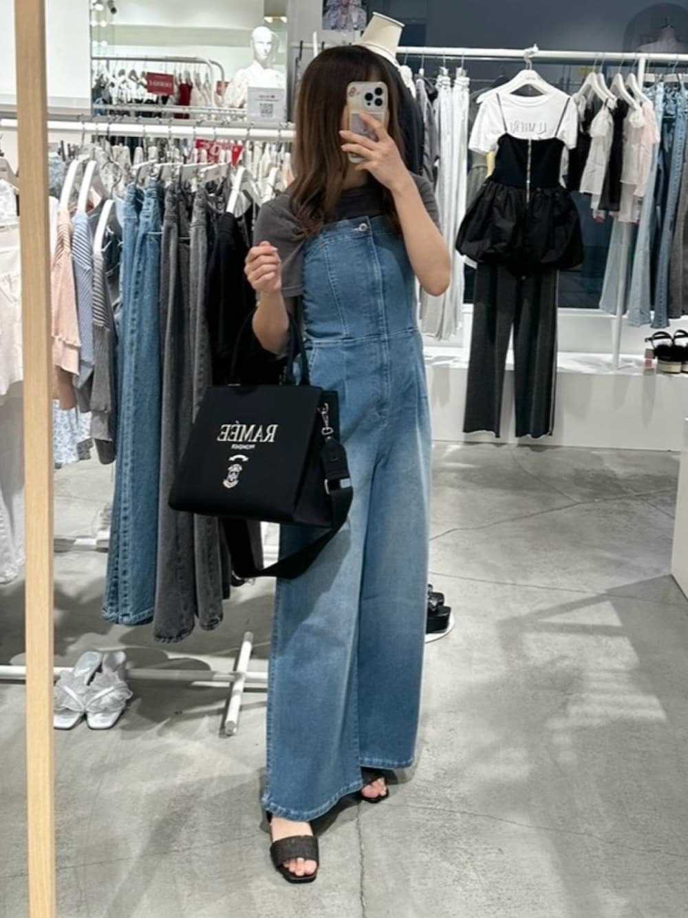 ブルー系のサロペット/オーバーオール、ブラック系のTシャツ/カットソー、ブラック系のサンダルを着用したレディースの夏コーディネートの3枚目の写真