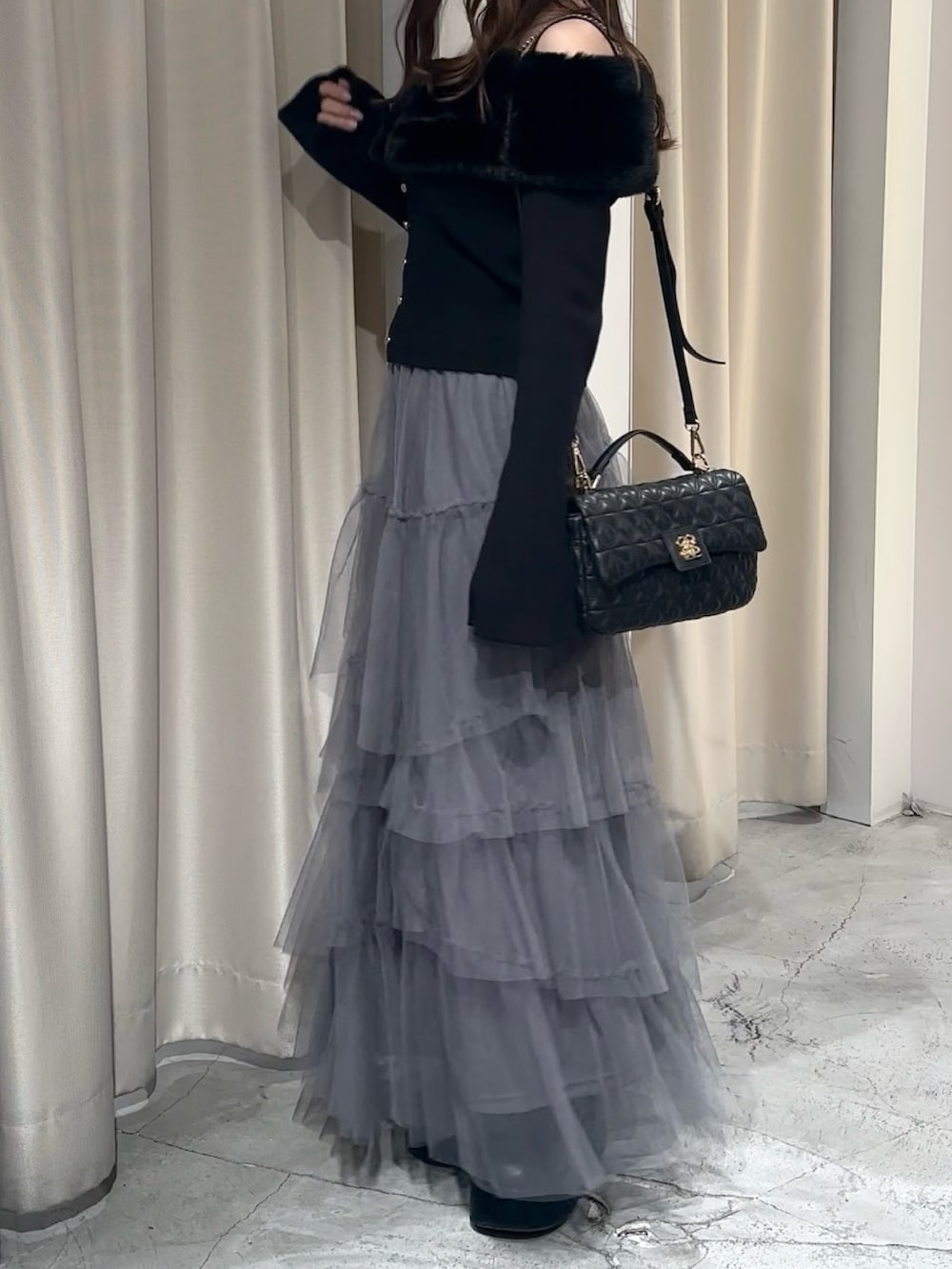 ブラック系のブーツ、グレー系のスカート、ブラック系のニット/セーターを着用したレディースの冬コーディネートの6枚目の写真