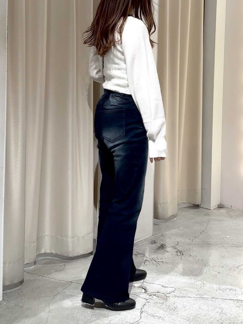 ブルー系のデニムパンツ、ホワイト系のニット/セーター、ブラック系のショルダーバッグを着用したレディースの冬コーディネートの7枚目の写真