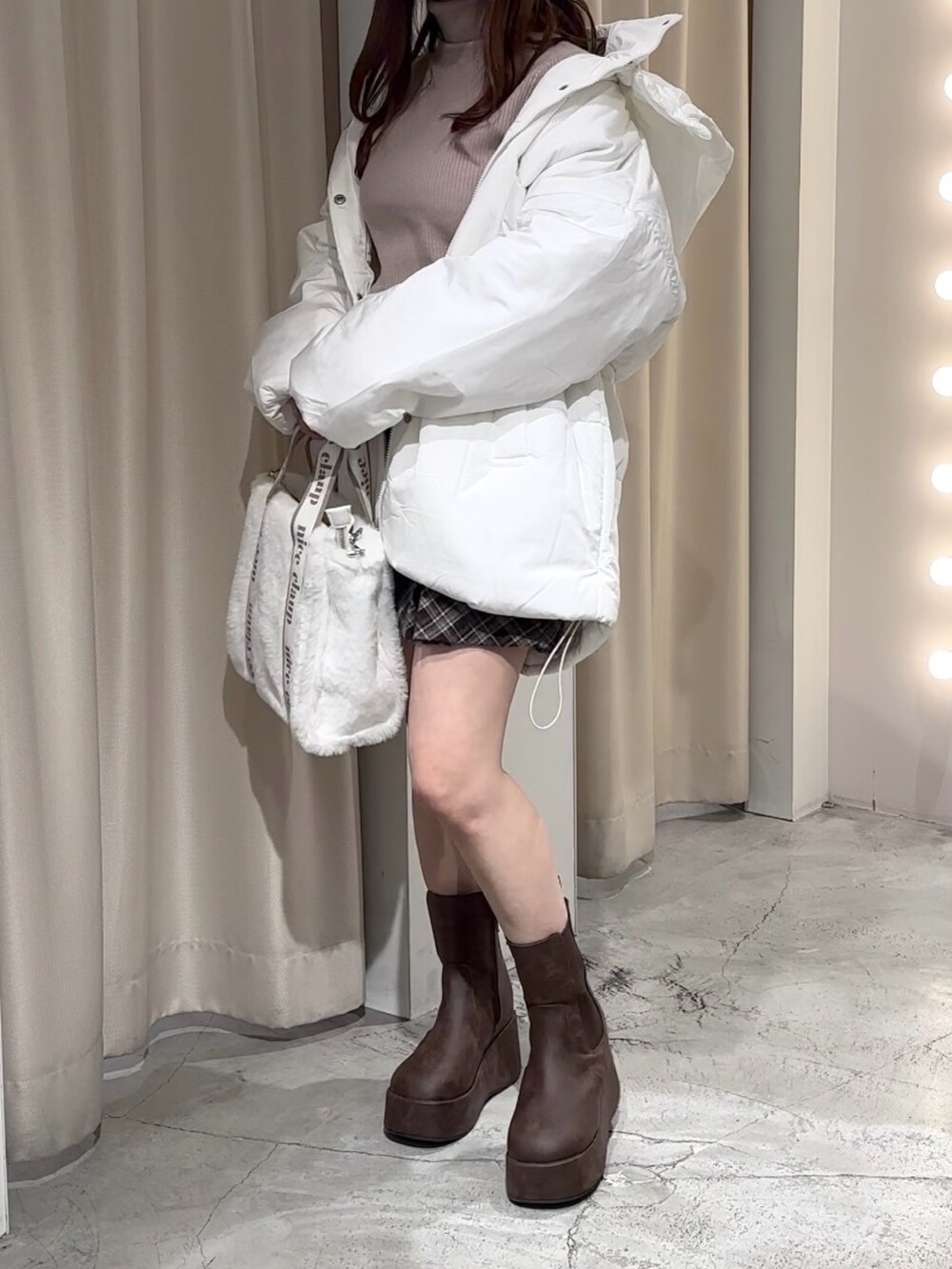 ホワイト系のダウンジャケット/コート、ブラウン系のスカート、ベージュ系のニット/セーターを着用したレディースの冬コーディネートの2枚目の写真