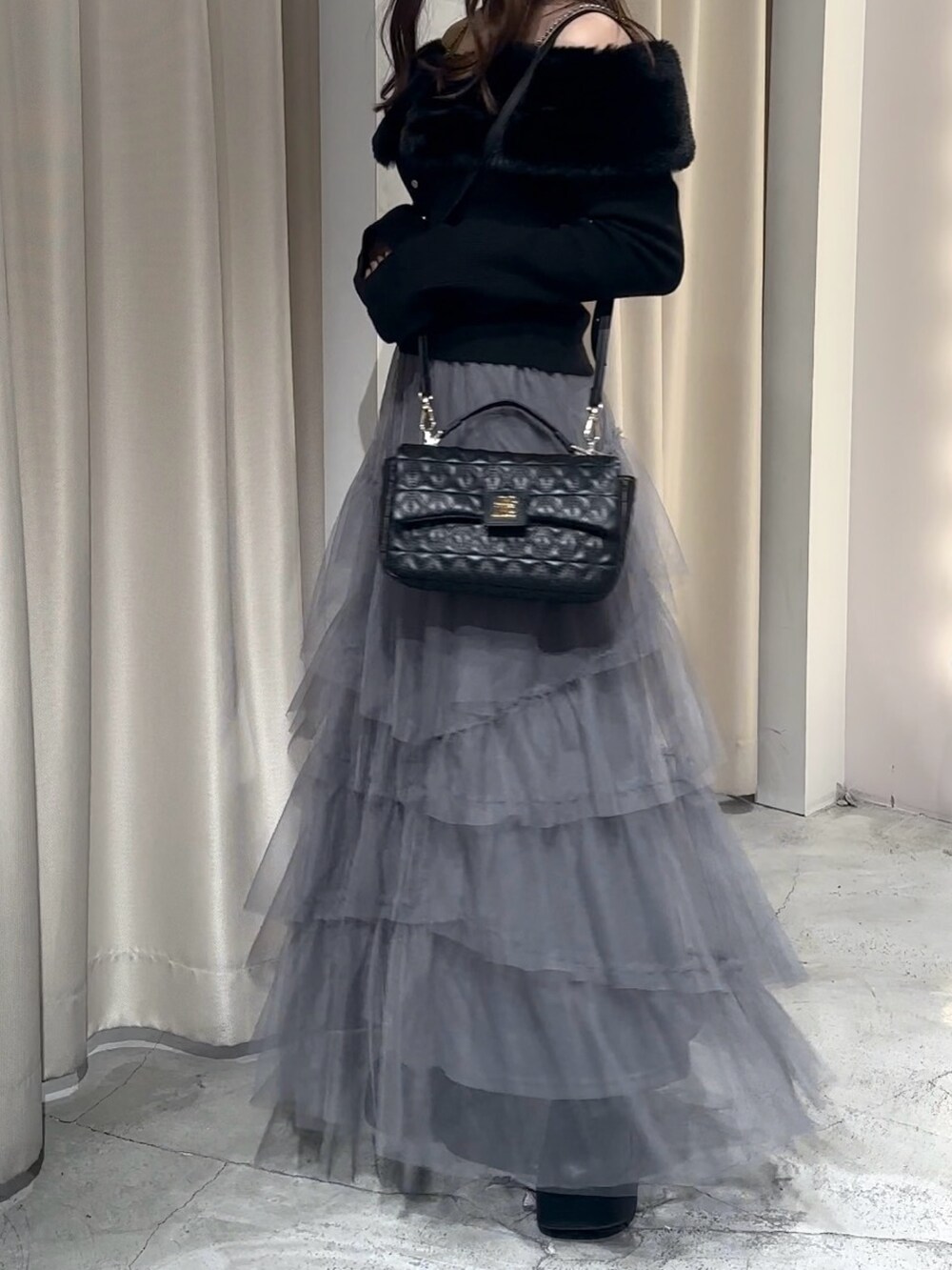 ブラック系のブーツ、グレー系のスカート、ブラック系のニット/セーターを着用したレディースの冬コーディネートの5枚目の写真