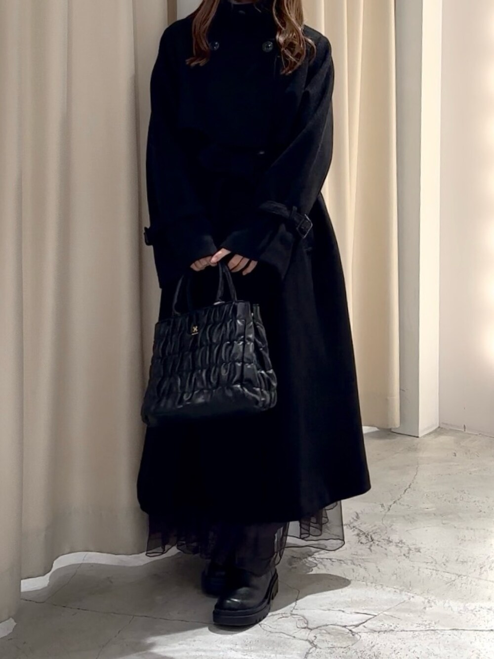 グレー系のニット/セーター、ブラック系のステンカラーコートを着用したレディースの冬コーディネートの4枚目の写真