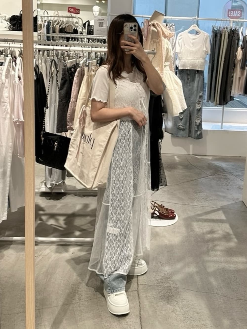 ホワイト系のワンピース、ブルー系のデニムパンツ、ホワイト系のトートバッグを着用したレディースの夏コーディネートの8枚目の写真